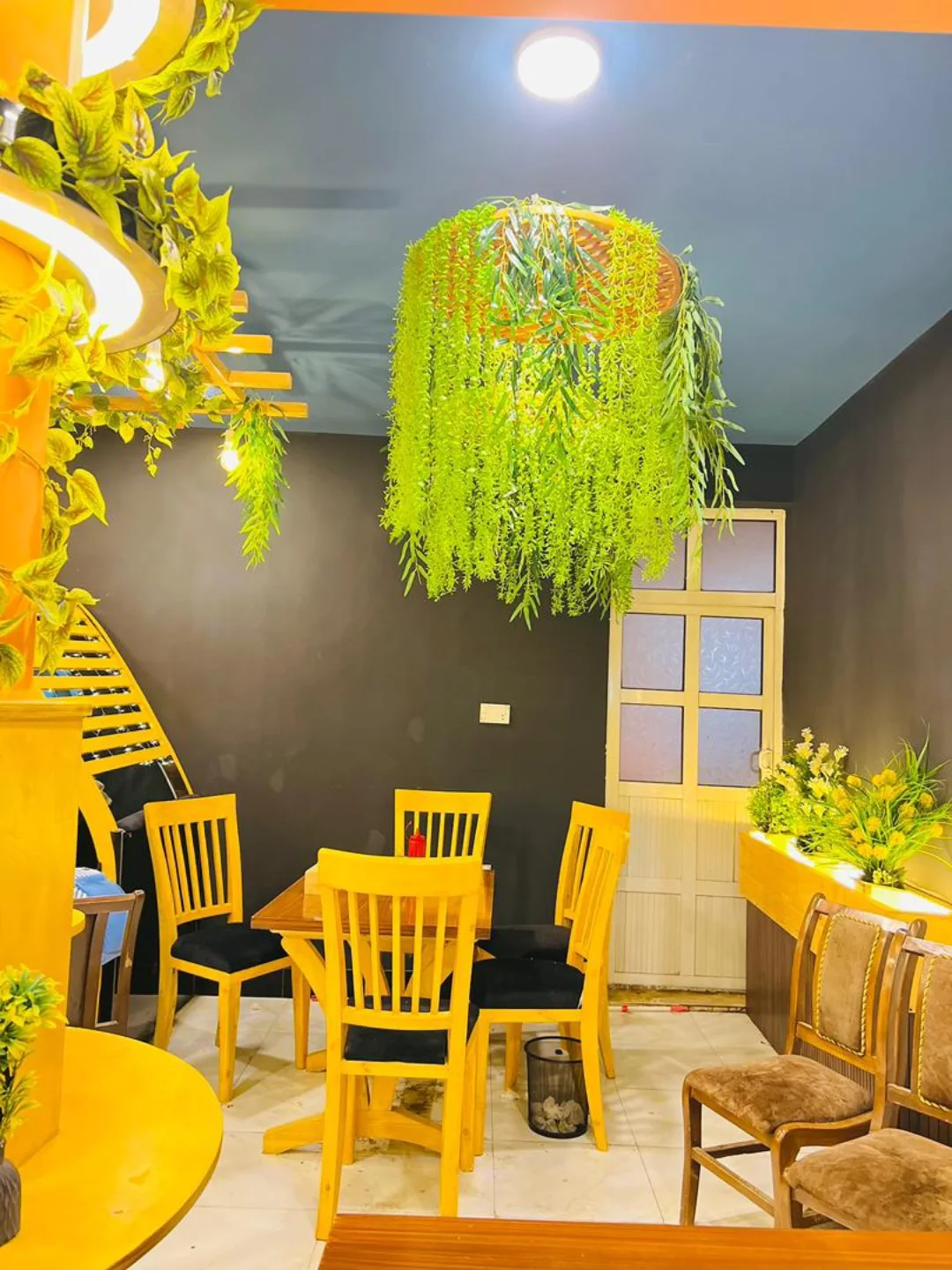 TURKEY KASHANA dining area with a hanging plant fixture above a wooden table and yellow chairs